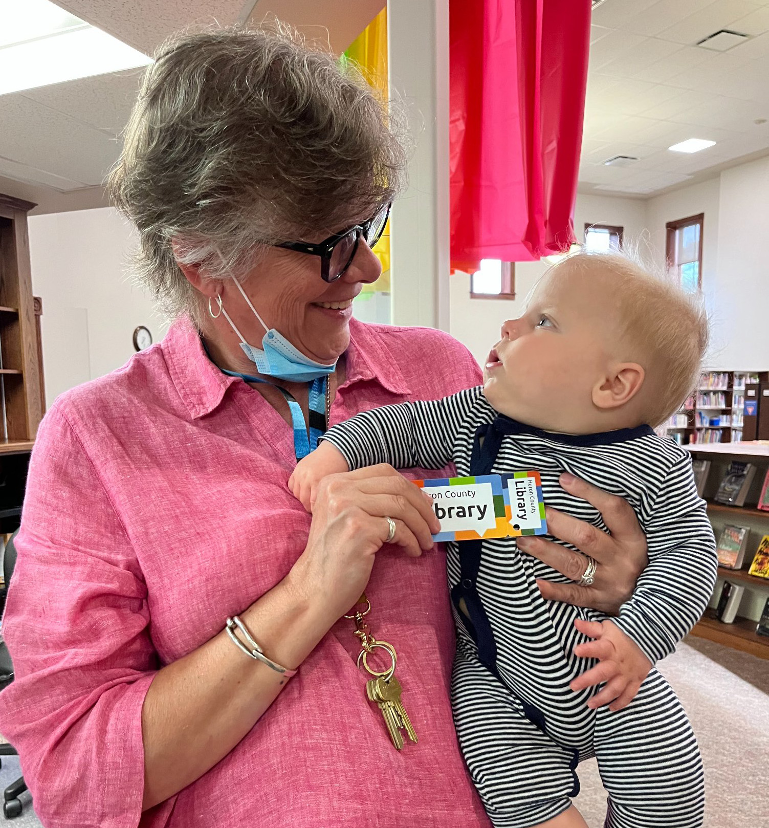 Photo of a library staff member giving a baby their first library card.