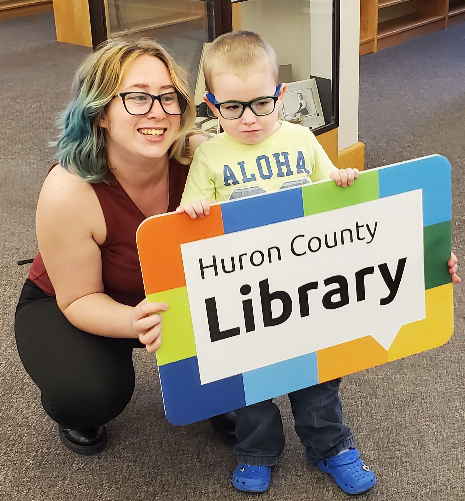 Image of a woman and a young boy holding a giant Huron County Library card